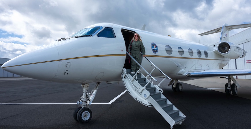 Photo depicts Professor Erin Hestir boarding a plane with a NASA logo on it in South Africa.
