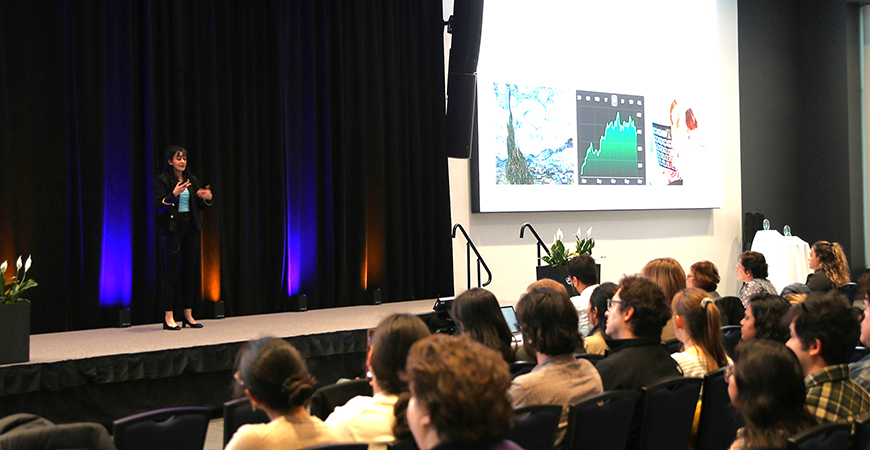 Group of individuals attending event with grads student presenting on stage