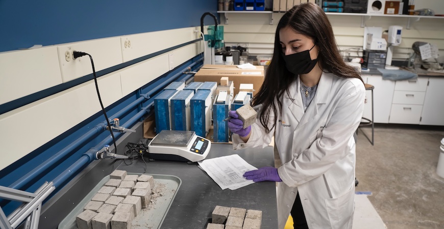 Professor Marina Garcia Lopez-Arias is pictured holding a block of concrete in her lab at UC Merced.